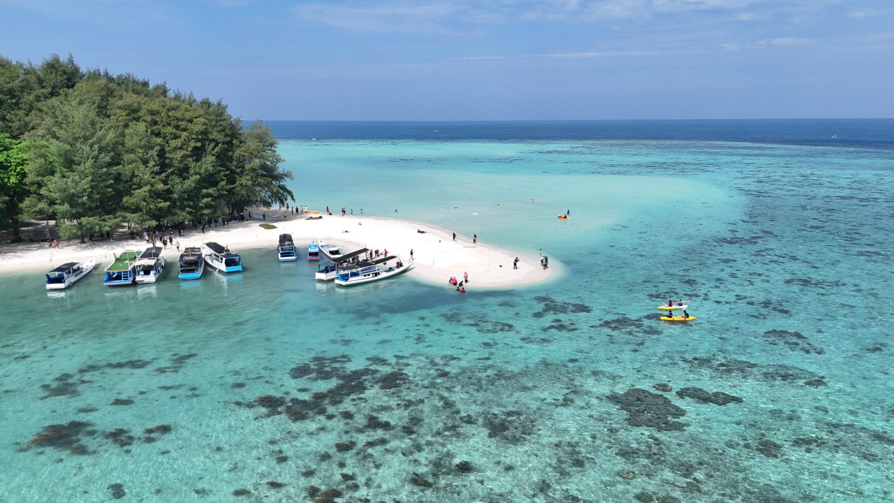 Perairan dangkal jernih biru-toska Kepulauan Karimunjawa — terumbu karang dan pasir putih terlihat dari permukaan air